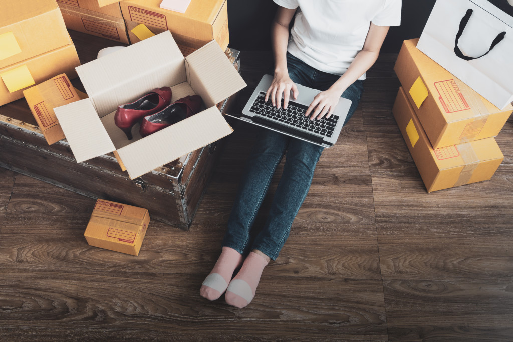 a woman working on her computer beside some boxes